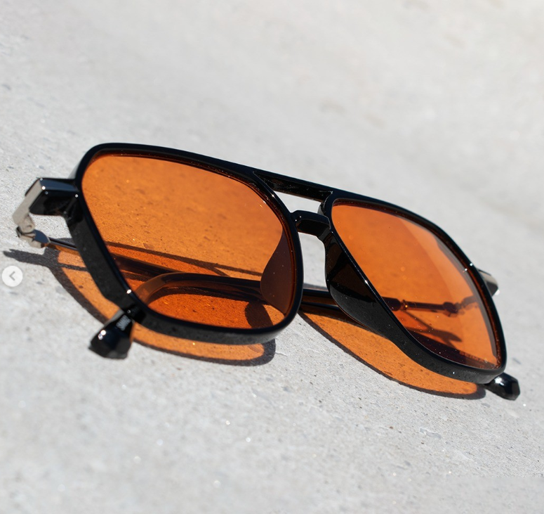 Armazón aviador negro con lentes naranja bajo la luz del sol